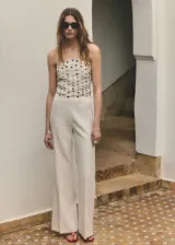 Top de tirantes finos color blanco con estampado de lunares negros, diseño fruncido y escote recto.