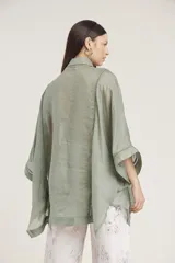 Camisa de manga ancha, color verde salvia, con cuello camisero y cierre frontal de botones. Presenta detalles de pespunte decorativo en el canesú frontal.