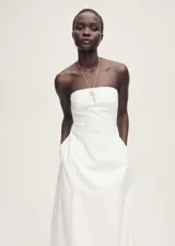 Vestido largo de diseño evasé con escote palabra de honor y bajo abullonado. Cuenta con cierre de cremallera en la parte posterior y bolsillos laterales.