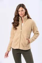 Campera beige de poliéster con textura sherpa, cierre frontal con cremallera marrón y bolsillos laterales.