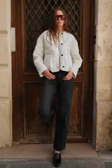 Chaqueta acolchada de cuello redondo y manga larga, con cierre frontal de botones y dos bolsillos delanteros de plastrón. Presenta un diseño de costuras en forma de rombos.