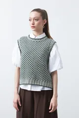 Chaleco tejido de algodón y acrílico, color rojo y blanco con patrón geométrico. Tiene cuello redondo y bordes acanalados en rojo.