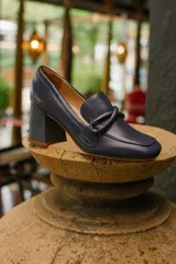 Zapato de cuero rojo con aplique decorativo en el empeine y tacón cuadrado.