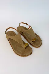 Sandalias de gamuza color tostado, con tira de dedo, hebilla ajustable en el talón y detalle metálico dorado.