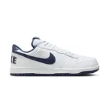 Championes Nike Big Low blancos con detalles en azul marino. Presentan una parte superior de cuero real y sintético, superposiciones cosidas, orificios de ventilación en la puntera y suela de goma.
