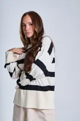 Sweater Bremer con cuello redondo y mangas largas ligeramente amplias. Diseño a rayas horizontales en color crudo y negro.
