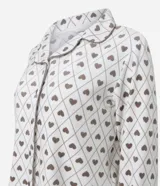 Pijama estilo americano de dos piezas confeccionado en plush. Incluye camisa de manga larga con cuello solapa y cierre frontal de botones, y pantalón largo con cintura elástica y cordón ajustable. Presenta un estampado geométrico de corazones sobre fondo claro.