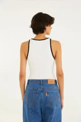 Top tipo musculosa de tejido acanalado blanco, con escote cuadrado y ribetes negros en el borde del escote y las sisas. Presenta doble tirante fino negro.