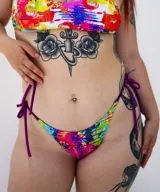 Pantie de bikini con estampado abstracto multicolor y tiras laterales de ajuste en color violeta.