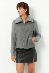 Tapado corto negro de paño con mangas y cuello tejidos, cierre metálico y bolsillos.