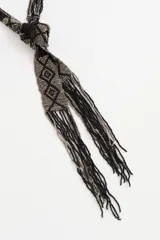 Collar largo tipo bufanda de cuentas de vidrio, con diseño geométrico en tonos negro y plateado, terminado en flecos.