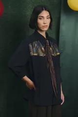 Camisa negra de manga larga con canesú frontal estampado con motivos artísticos de bodegón. Incluye una corbata fina integrada del mismo tono.