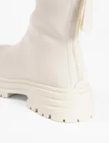 Botas de caña media color crema, con plataforma dentada y cierre metálico en la parte trasera.