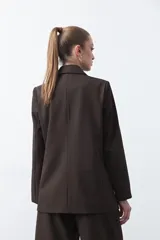 Blazer sastrero negro de doble botonadura con botones marrones, cuello solapa y mangas tres cuartos. Tiene dos bolsillos delanteros con solapa.