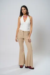 Pantalón de tiro alto color beige, con cierre frontal con cremallera y botón, bolsillos delanteros y traseros, y corte evasé en el bajo.