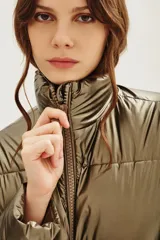 Campera puffer de cuello alto con cierre frontal, acabado metalizado y bolsillos laterales con cierre.