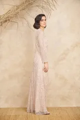 Vestido largo color rosado, con diseño de manga larga y cuello redondo, completamente bordado con lentejuelas y abalorios formando patrones geométricos y florales.