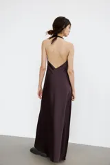 Vestido largo de satén negro con cuello halter y escote fluido. Presenta cierre con cremallera oculta en la espalda y lazada en el cuello.
