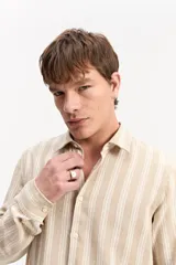Camisa de manga larga con diseño texturado a rayas en tonos beige y blanco, cuello camisero tradicional y cierre frontal con botones.