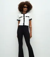 Pantalón de corte flare confeccionado en punto roma, con cintura estructurada, detalle de hebilla decorativa, cierre frontal y bolsillos posteriores.