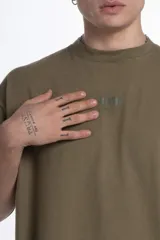 Remerón de jersey pesado color verde oliva, con cuello redondo y manga corta. Presenta un estampado sutil en el pecho y un estampado más grande en la espalda.