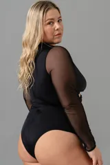 Body negro de lycra con efecto lurex y mangas largas de microtul. Escote en V con aro en el centro y tiras.