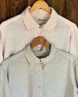 Camisa a rayas verticales, con cuello clásico y cierre frontal con botones.