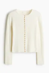 Saco corto en punto acanalado de color blanco, con cuello redondo y tapeta frontal con múltiples botones.