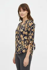 Blusa estampada de viscosa con diseño abstracto en tonos beige, negro y marrón, escote en V con cuello mao y mangas tres cuartos con detalles de lazos en los puños.
