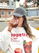 Gorro de béisbol de color gris oscuro (obsidian) con efecto lavado, confeccionado en algodón. Presenta un bordado frontal de un ají picante rojo y verde.