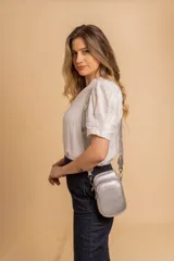 Bandolera compacta color rojo con textura de cuero, correa regulable y desmontable con diseño de rayas rojas y blancas. Cuenta con bolsillos frontales y cierre, interior forrado en tela.