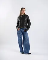 Campera de cuero sintético negro estilo motero con cuello mao, cierre frontal, bolsillos con cierre y detalles de tachas en hombros y mangas.