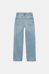Jeans de mujer, tiro alto, color azul medio con efecto desgastado (lavado claro en muslos y oscuro en bordes). Corte recto y ancho (mom fit) con cinco bolsillos y cierre frontal de botón y cremallera.