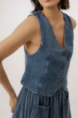 Chaleco de denim azul con cuello en V, cierre frontal con botones metálicos y pespuntes en contraste.
