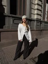 Blazer oversize blanco con finas rayas verticales oscuras, solapas clásicas y cierre frontal con botones.