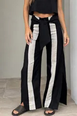 Pantalón de lino de pierna amplia, color negro con franjas verticales frontales en contraste de color beige y lazo ajustable en la cintura.