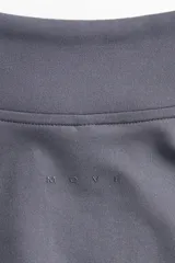 Campera deportiva gris de corte ajustado con cuello elevado, cierre frontal completo y mangas largas con abertura para el pulgar.