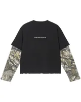 Remera boxy de manga larga con diseño efecto doble capa, cuerpo negro de algodón y mangas de tejido waffle con estampado camuflado Realtree. Cuenta con detalles bordados en el pecho.