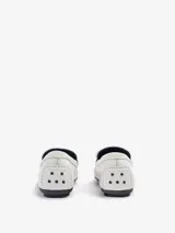 Mocasín plano Bert de punta redondeada, confeccionado en cuero vacuno color blanco con costuras artesanales y detalle de borla de flecos en el empeine, sobre suela de goma.