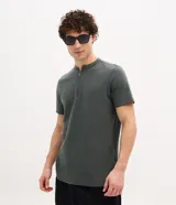 Remera de algodón peruano verde militar, de corte slim, con cuello padre y cierre frontal parcial de cremallera metálica, y mangas cortas.