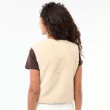 Chaleco sin mangas de textura tipo corderito en color beige, con cierre frontal de botones a presión y ribetes al tono.