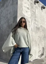 Poncho de hilo liviano en color verde claro, con diseño de cuello alto y caída fluida. Prenda versátil ideal para media estación.