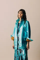 Blazer de cuero metalizado en color dorado, con cierre frontal de botones de nácar y bolsillos frontales tipo parche.