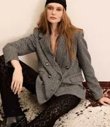 Blazer de tweed gris con diseño de espiga, doble botonadura, solapas de muesca, bolsillos cargo frontales y corte clásico.