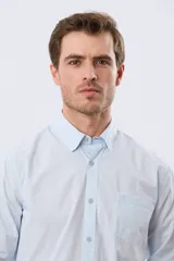 Camisa celeste de manga larga confeccionada en algodón, con cuello camisero, cierre frontal de botones, bolsillo en el pecho y diseño de cuadros sutiles.