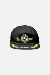 Gorra con visera plana y cierre snapback, confeccionada en algodón negro con corona no estructurada. Cuenta con detalles bordados en tonos dorados y verdes en el frente y la visera.