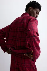 Pijama de dos piezas confeccionado en franela de algodón. Incluye una camisa de manga larga con cuello inglés, botones frontales y bolsillo en el pecho, junto con un pantalón de corte recto con cintura elástica y cordón ajustable.