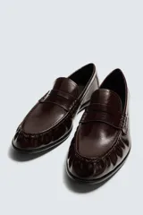 Mocasín de vestir para hombre en color negro, con acabado brillante, detalle de antifaz en el empeine y punta redondeada.