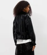 Campera tipo trench coat en PU color negro, de manga larga, con solapa amplia, hombreras decorativas y cinturón ajustable con hebilla en la cintura.