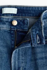 Jean tobillero de corte recto y tiro alto en denim de algodón con leve elasticidad. Presenta diseño de cinco bolsillos, cierre de botón y cremallera, y pliegues marcados al frente y en la espalda.